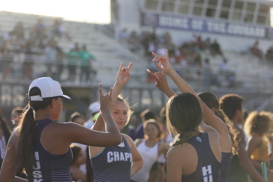 Girls Varsity 4x400 meter relay team chanting Family with a husky symbol in the air.