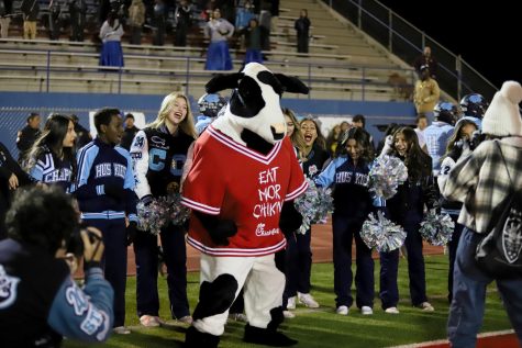 Varsity cheer dances with the Chick-fil-a mascot before kickoff. 
