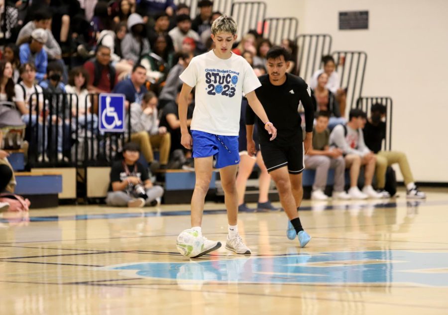 Senior Patrick Silva dribbles the ball in the game against faculty members. The indoor soccer game took place in the main gym during the las period of the day.