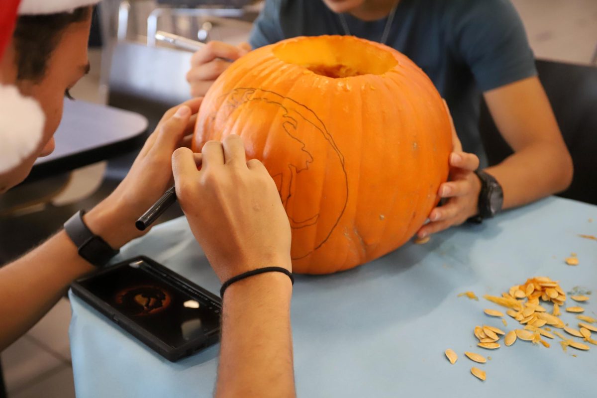 After choosing a design for their pumpkin, Seniors Patrick Whearley Sanchez and Ivanna Cho get to drawing. 