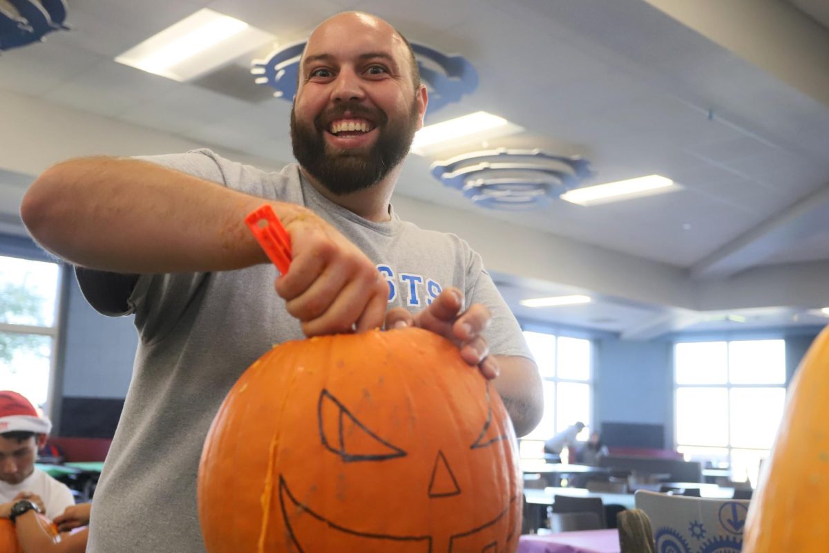 Smile for the camera! TSA Advisor, Mr. Logsdon takes a perfect opportunity to get his picture taken while carving out his pumpkin.