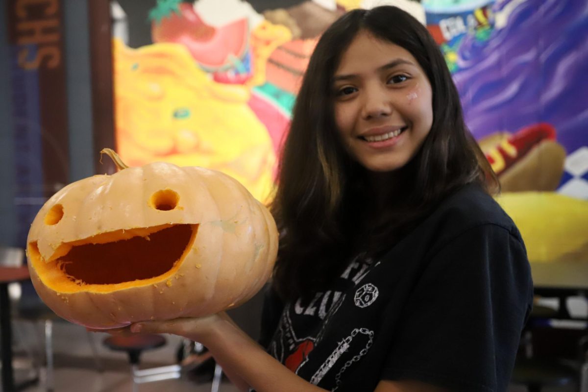 Having finished her pumpkin, _____ poses to show off her latest creation.