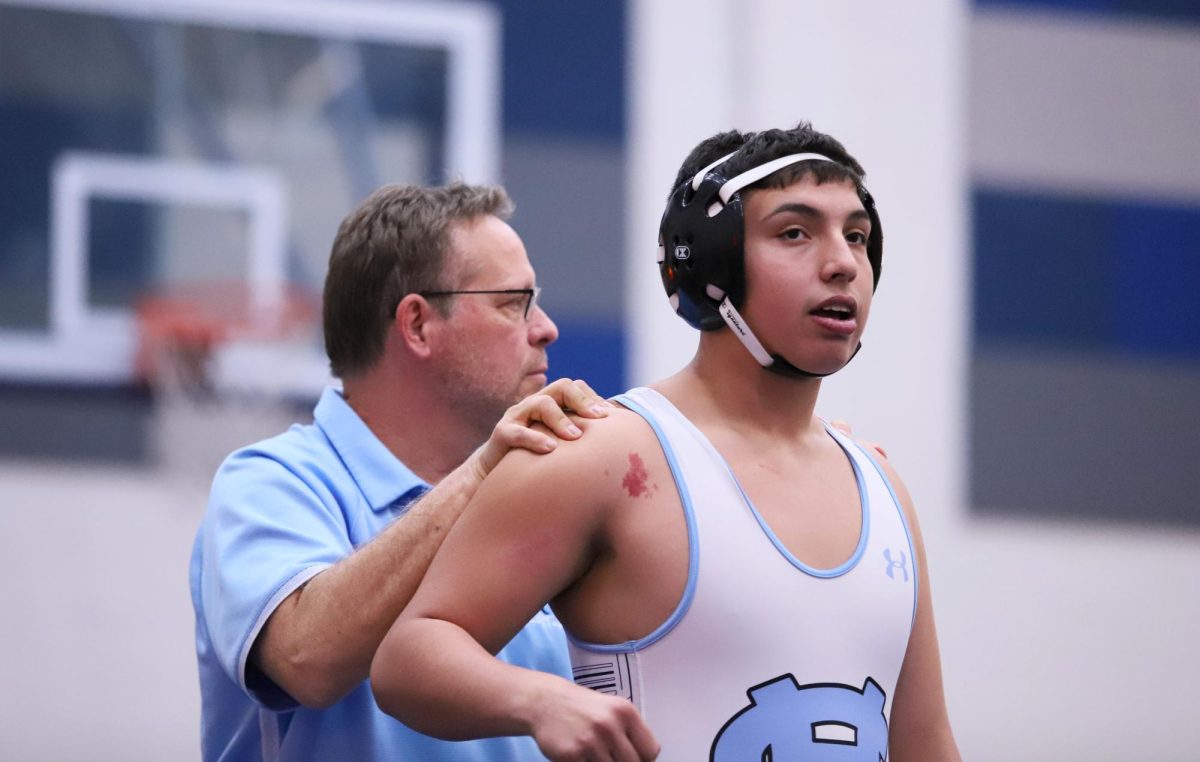 Before Sophomore Jorge Martinez match, coach Karl Queen helped him stretch his shoulders out. "It is super important to warm up before a match," teammate Sergio Vargas said. "You have to get your mentality right. You have to stay warm in order to give your best performance and not feel stiff."