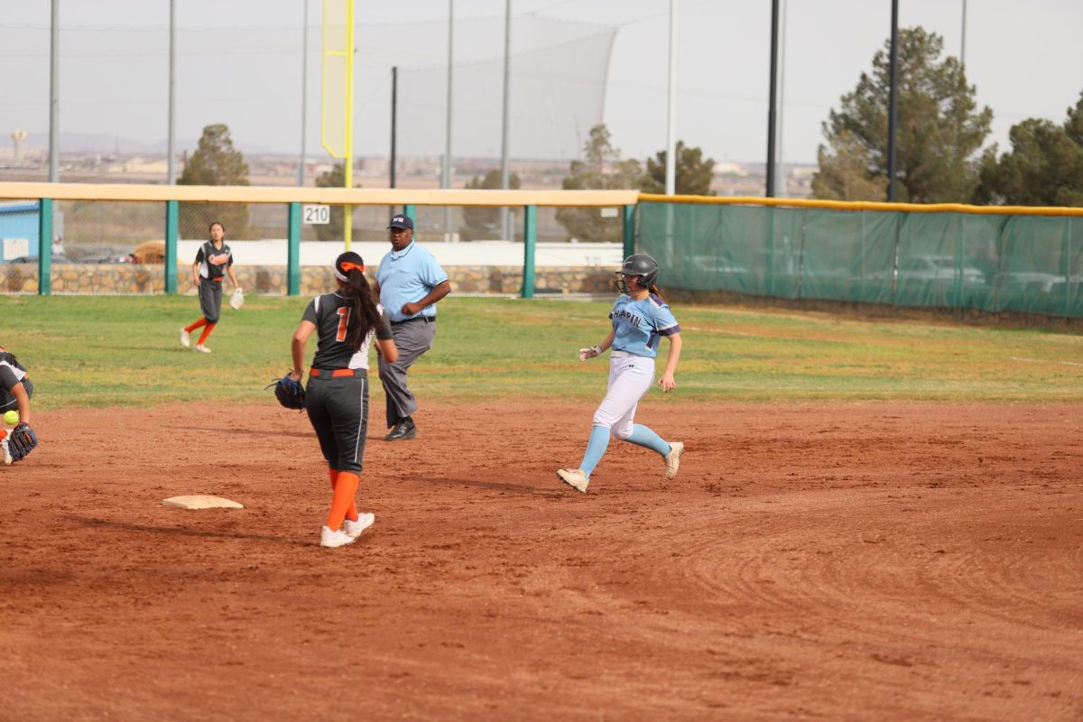 Player approaches second base while the opposing team's center field runs to grab the ball
