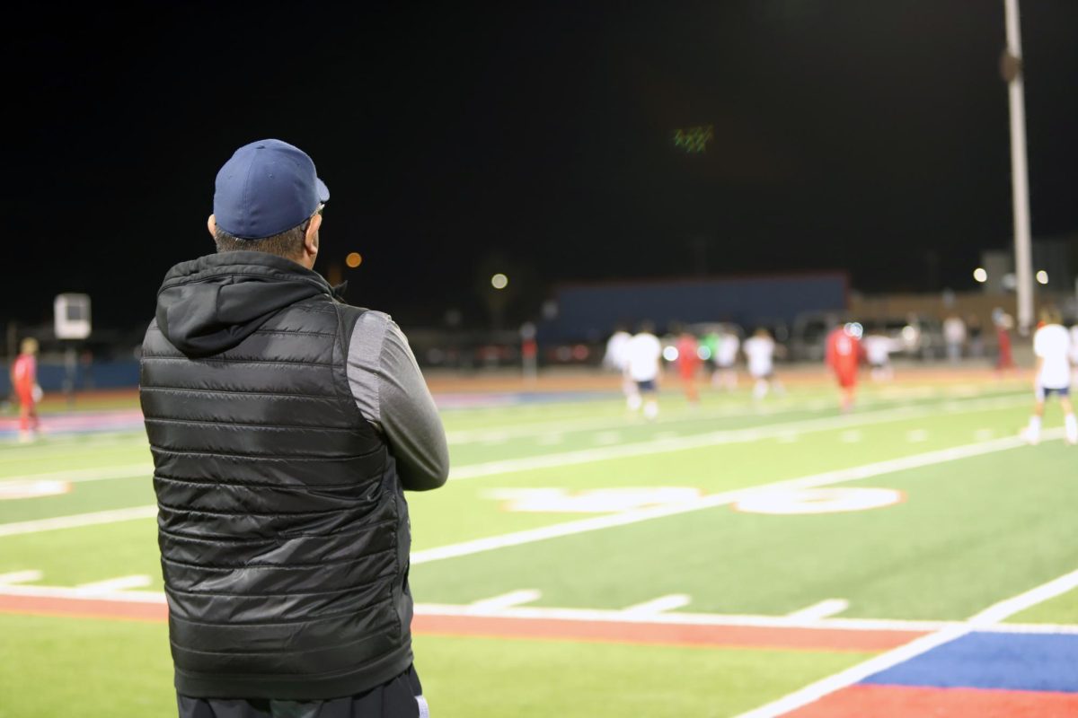 Mentor. In this pic the coach of JV boys soccer is seen observing his teams performance. The coach is the main leader of the team and has taught his players many different things. "Coach is the one we all learn from and look up to." JV boys soccer defender Remi said.