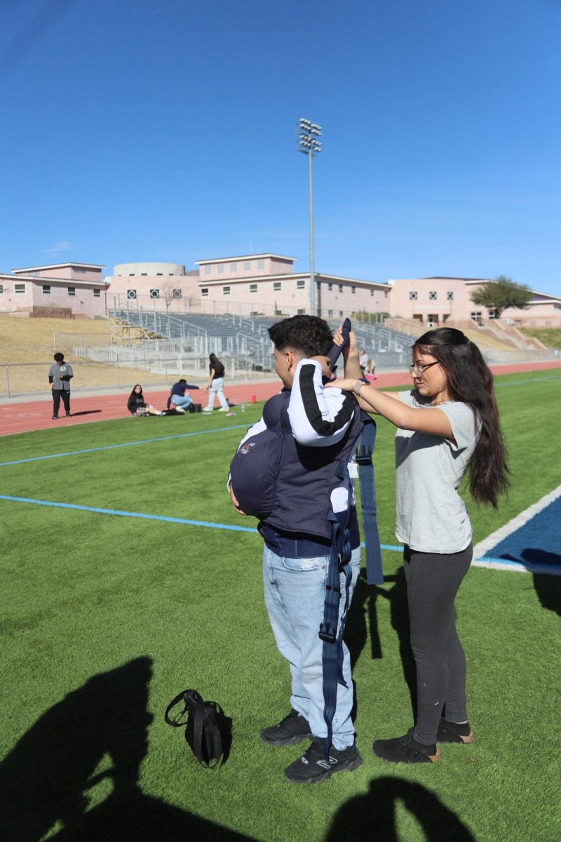 Students help others put on pregnancy bellies and prepare them for the next activity.